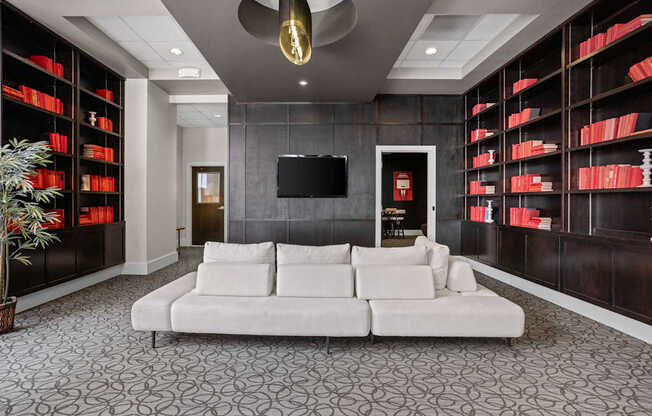 A living room with a white couch and a television on the wall.
