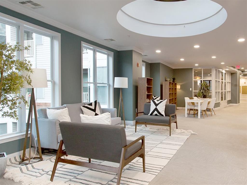 Couches, chairs and lamps in front of tall windows in the Clubhouse at Prospect Place, Hackensack NJ