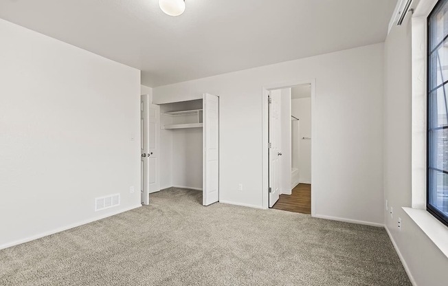A bedroom with a carpeted floor and white walls at Tanglewood Apartments, Oak Creek, WI