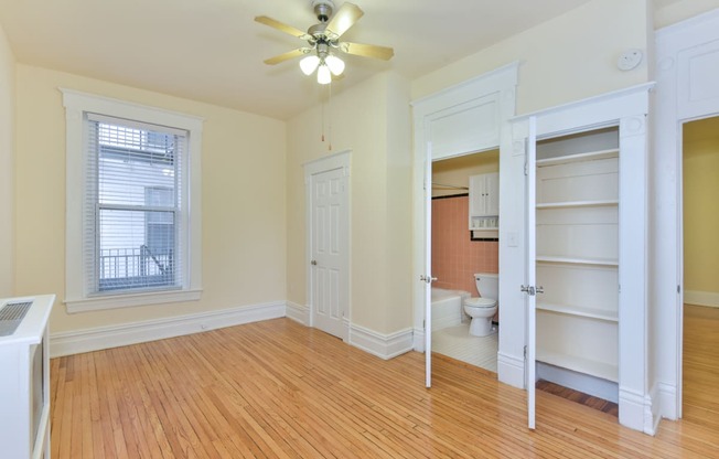 vacant bedroom with hardwood floors, ceiling fan, large closet and view of bathroom at dupont apartments in washington dc