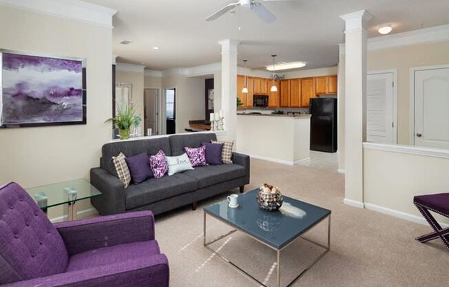 a living room with purple furniture and a kitchen in the background