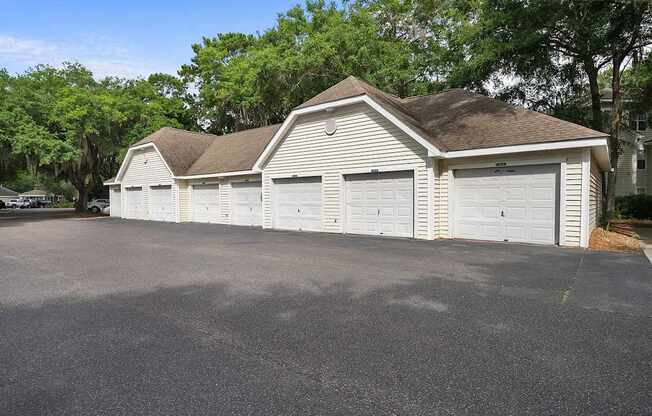 A two-car garage with a brown roof is surrounded by trees.