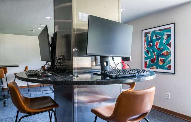 A modern workspace with a round table, two chairs, and a computer setup.