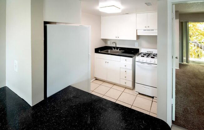 a kitchen with white appliances and black counter tops