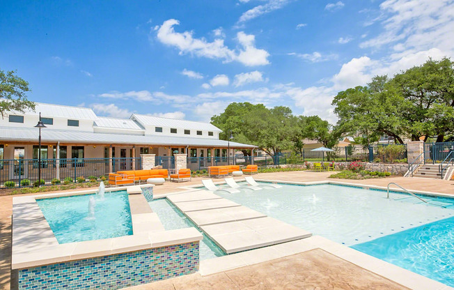 A swimming pool with a waterfall and a building in the background.