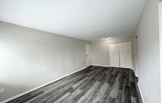 an empty living room with wood floors and white walls