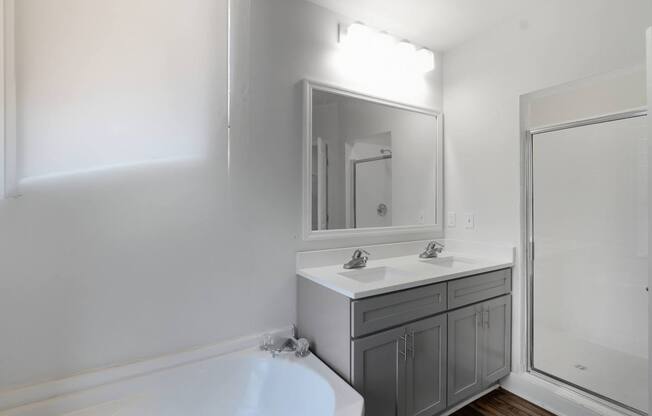 A white bathroom with a tub, sink, and mirror.