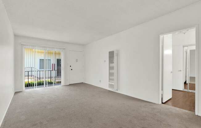 an empty living room with a door to a balcony at Olive Tree Apartments, Torrance California