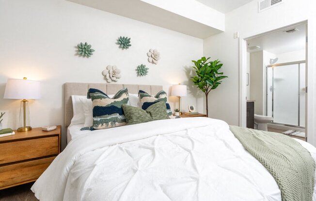 A bedroom with a large bed and a green plant.