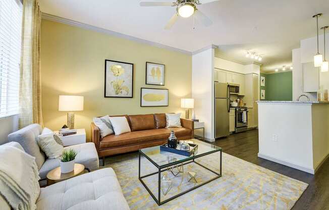 A living room with a grey couch, a coffee table, and a ceiling fan.