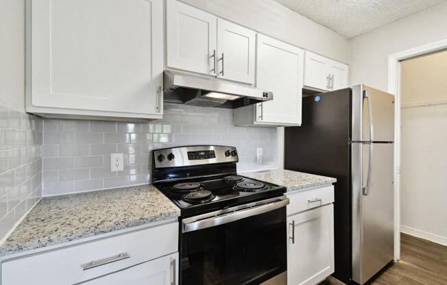 a kitchen with white cabinets and black appliances