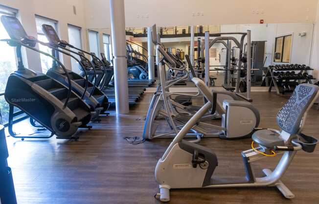 a gym with cardio equipment and weights on a wooden floor