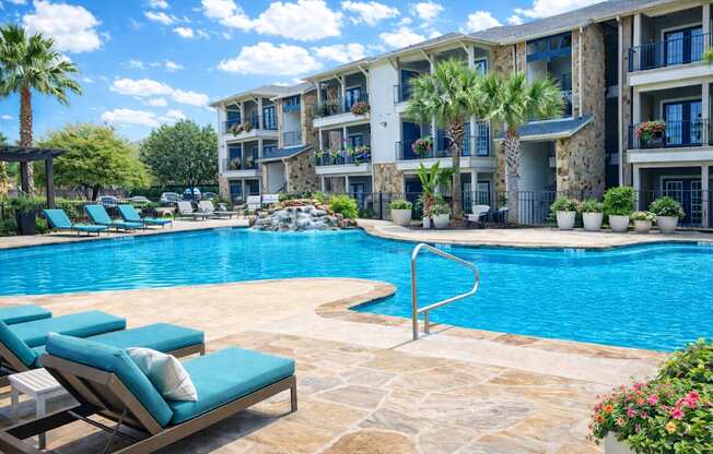 A pool surrounded by lounge chairs and palm trees.