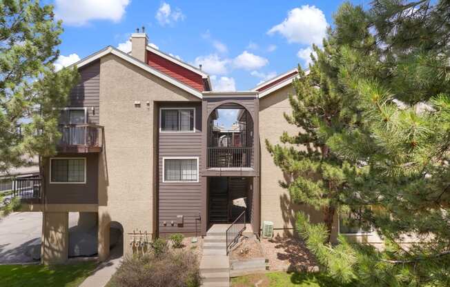 an exterior view of a tan house with a balcony and trees