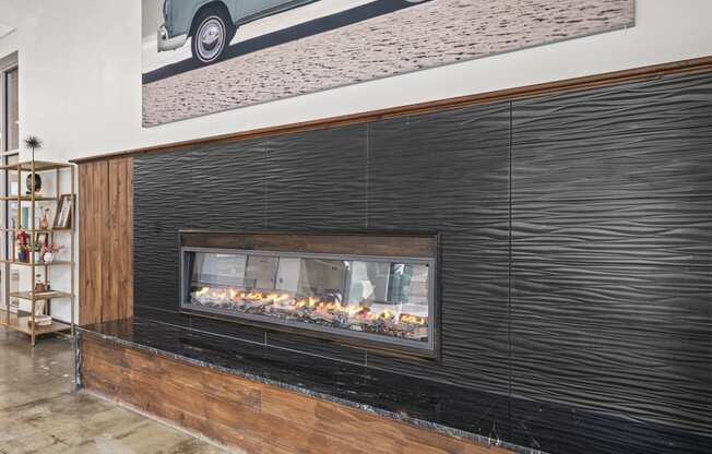 a fireplace with a wooden mantle and a painting of a car on the wall above it  at The Icon, Richmond, 23230