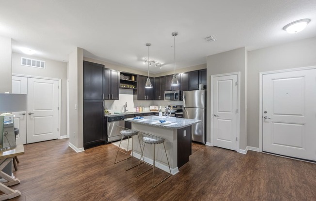a kitchen with an island and stainless steel appliances and dark cabinets