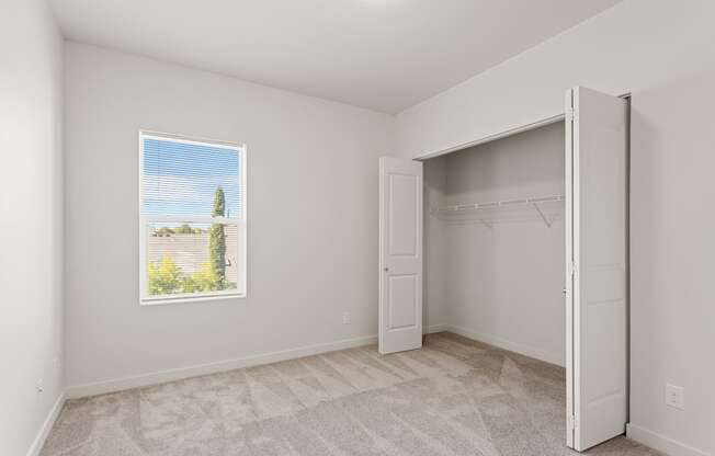 A room with a carpeted floor and a window showing a tree and houses outside.