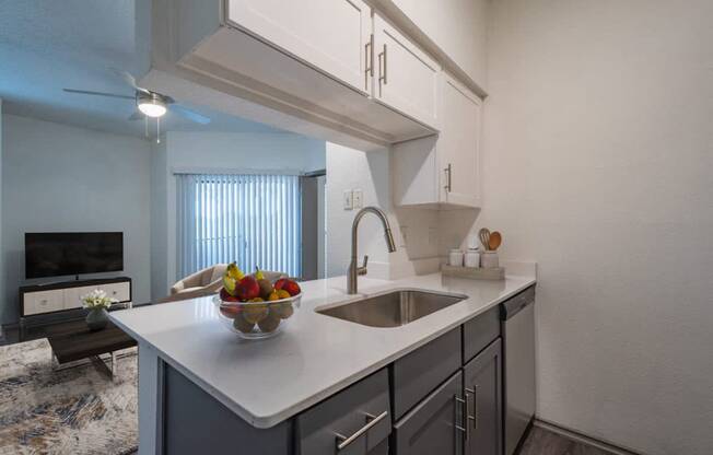 a kitchen with a sink and a bowl of fruit