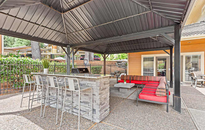 A patio with a bar and chairs under a roof.