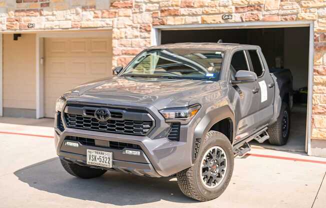 A grey Toyota truck is parked in front of a garage.