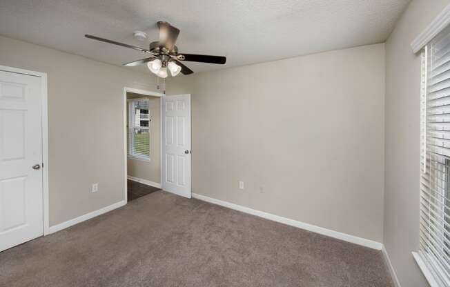an empty living room with a ceiling fan and window