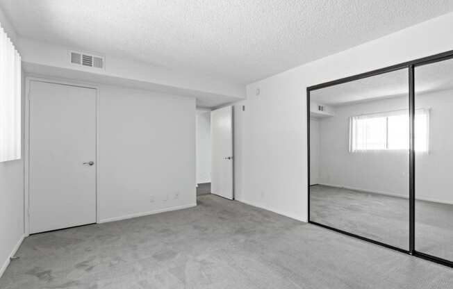 an empty living room with a large mirror and white walls