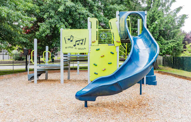 A blue slide in a playground with a yellow and black sign.