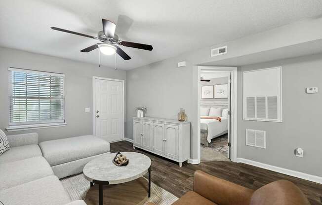 A living room with a white couch, a brown chair, and a ceiling fan.