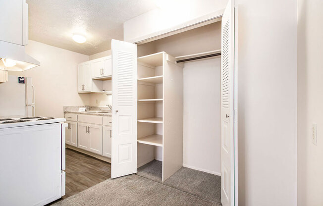 a renovated kitchen with white appliances and a closet with shelves