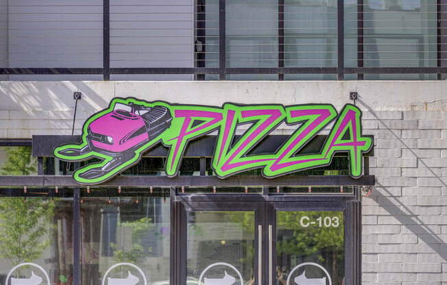 a neon sign that reads pizza on top of a building