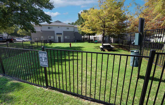 A black fence surrounds a green field with a sign that says "No Parking".