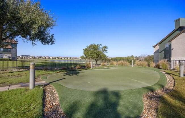 a putting green with a house and trees in the background at The Fairways at Star Ranch, Hutto, Texas