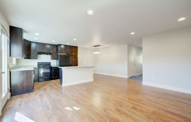 an empty living room and kitchen with wood flooring and black appliances at Copper Pines, Bozeman, MT