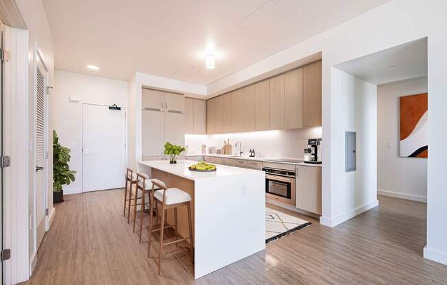 A modern kitchen with wooden floors and a white island.