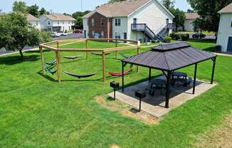 a picnic area with hammocks and a gazebo in a grassy yard