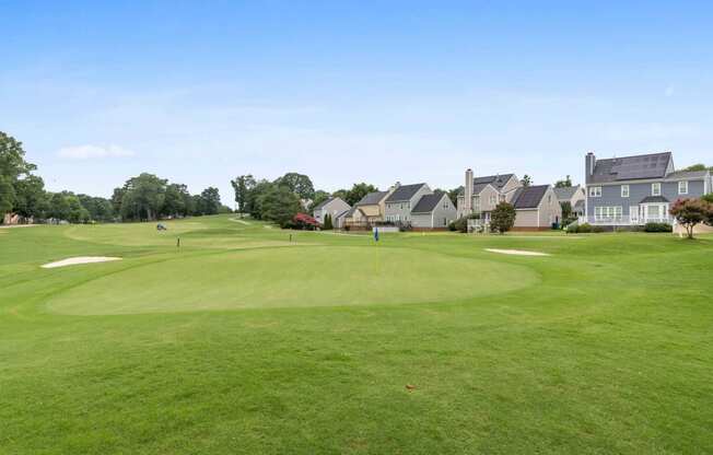 a view of a golf course with houses in the background