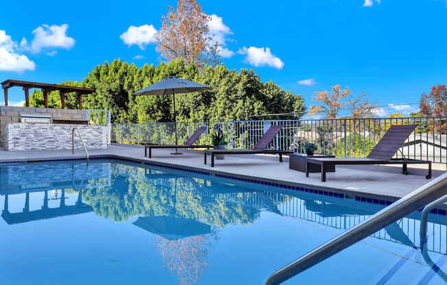 A pool with a black umbrella and a metal fence.