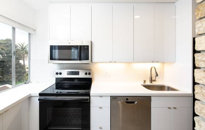 a kitchen with white cabinets and black appliances