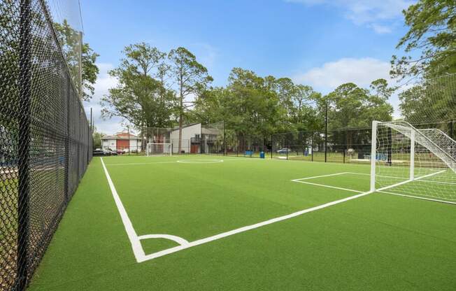 a soccer field with a goalie net and a building in the background