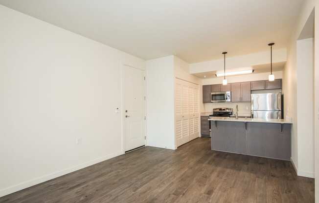 an empty living room and kitchen with a stainless steel refrigerator