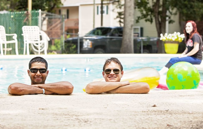 two young men laying on the side of a swimming pool