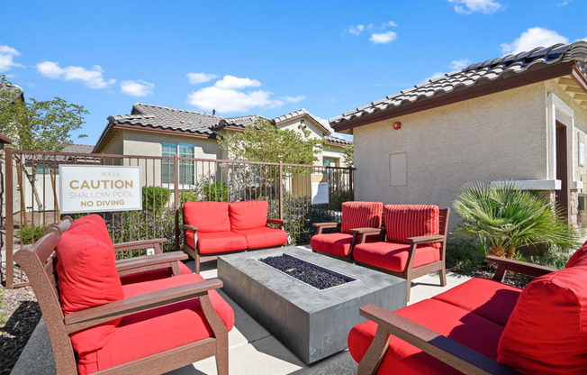 a patio with red chairs and a fire pit