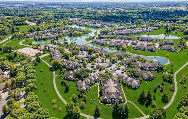 A bird's eye view of a residential area with houses, lawns, and a river.