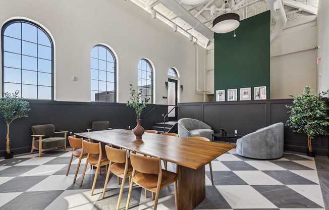 A long wooden table is surrounded by chairs in a room with a checkered floor.