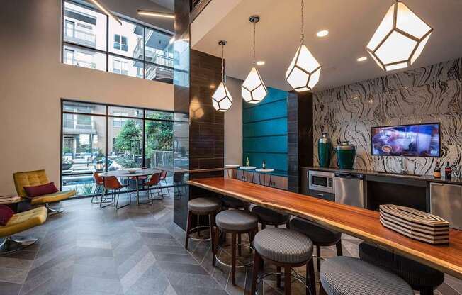 A modern bar area with a long wooden bar and stools.