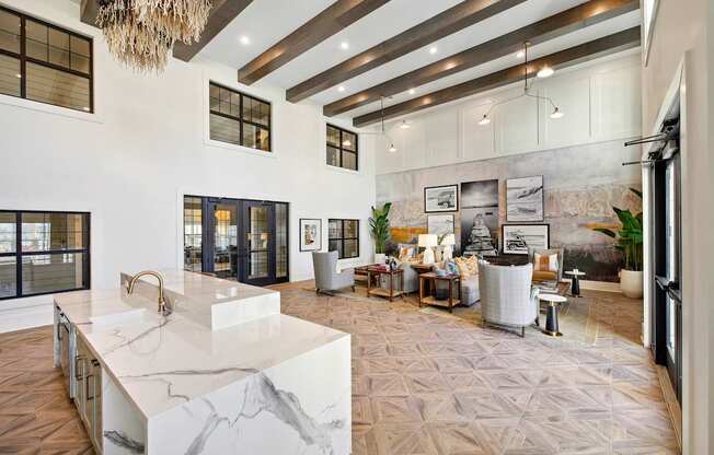 A modern kitchen with a marble island and a chandelier.