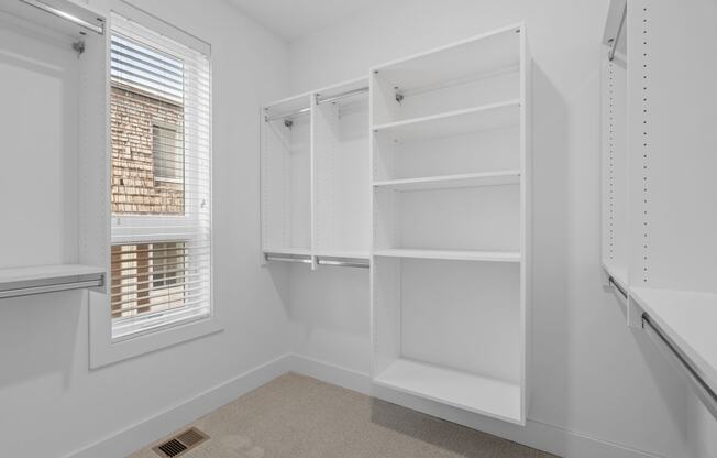 a white closet with white shelves and a window