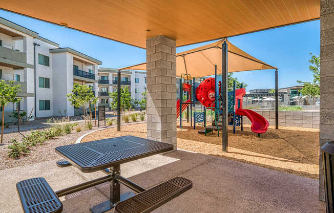 A playground with a red slide and a picnic table.