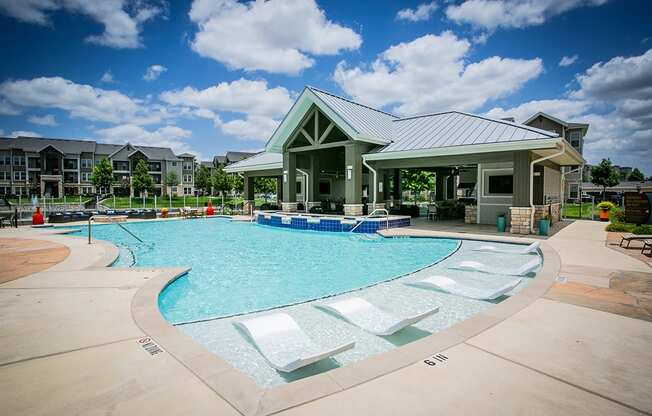 a resort style pool with lounge chairs and a clubhouse in the background