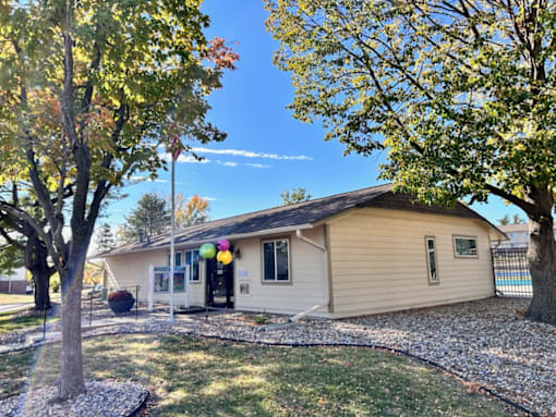 a small tan house with balloons in the yard